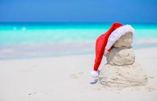 Little sandy snowman with red Santa Hat on white Caribbean beach photo