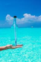 Bottle with a message in the hand background blue sky photo