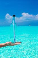 Bottle with a message in the hand background blue sky photo