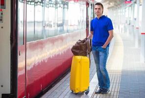 joven con equipaje en una estación de tren foto