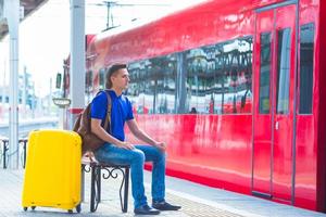 Young man with luggage at a train station waiting for Aeroexpress photo