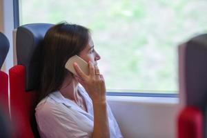 joven empresaria hablando por teléfono viajando en tren foto