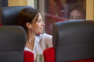 Young happy girl listening music traveling by train photo