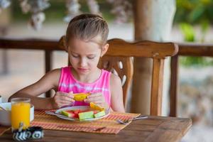 Adorable little girl having lunch at outdoor cafe photo