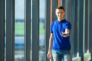 Young caucasian man holding passports and boarding pass at airport near window photo