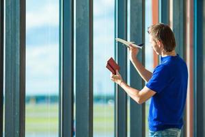 Young man with passports, boarding pass and aircraft toy model at airport photo