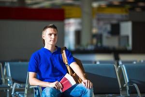 Young man holding passports and boarding pass at airport photo