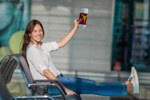 Happy woman with small model airplane and passports in airport photo