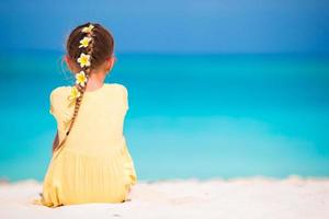 Adorable little girl with frangipani flowers in hairstyle on beach