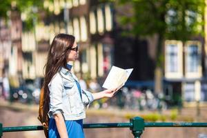 Happy young woman with a city map and backpack in Europe photo