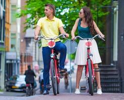 Young happy caucasian couple on bikes in old streets in Amsterdam photo