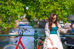 mujer joven feliz con un mapa de la ciudad en bicicleta en ciudad europea foto
