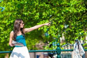 mujer joven feliz con un mapa de la ciudad en bicicleta en ciudad europea foto