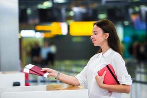 Young girl with passports and boarding passes at the front desk at international airport photo