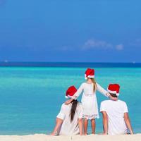 familia feliz con sombreros de santa en la playa durante las vacaciones de navidad foto