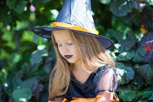 Portrait of happy little girl wearing witch costume with broom on Halloween photo