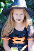 retrato de una linda niña con traje de bruja con escoba en halloween foto