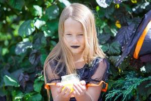 Portrait of happy little girl wearing witch costume with broom on Halloween photo