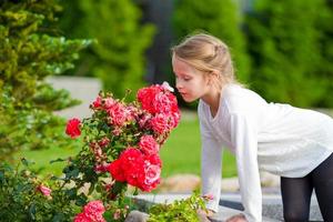 niña adorable que huele flores de colores en el día de verano