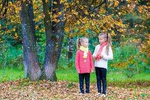 Two adorable girls in park at warm sunny autumn day photo