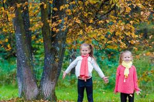 Two adorable girls in park at warm sunny autumn day photo