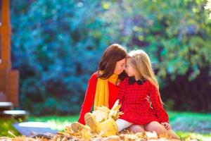 adorable niña con madre en el parque de otoño al aire libre foto