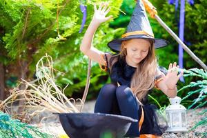 Happy little girl wearing witch costume on Halloween outdoors. Trick or treat. photo