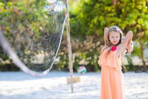 Little adorable girl playing voleyball on beach with ball photo