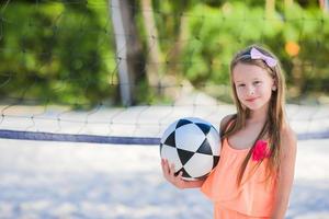 niña adorable jugando voleibol en la playa con pelota foto