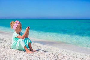 Little adorable girl with phone during beach vacation photo