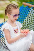 Adorable girl in hammock outdoor at tropical vacation photo