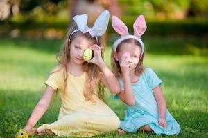 dos adorables hermanitas con orejas de conejo el día de pascua al aire libre foto