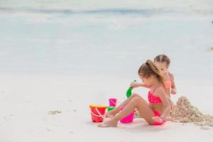 Little cute girls playing with beach toys during tropical vacation photo