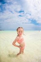 Adorable little girl have fun at tropical beach during vacation photo