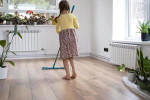 A girl dances with a mop to clean the floor in a new house - general cleaning in an empty room, the joy of moving, help with the housework photo