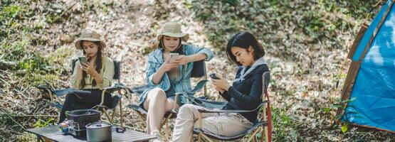 Group of girl friends with smartphone while camping in park photo