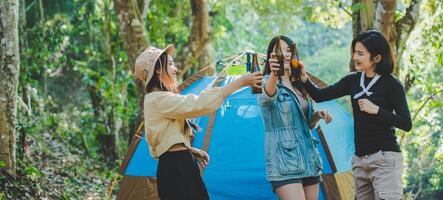 Young woman cheer and drink beverage front of camping tent photo