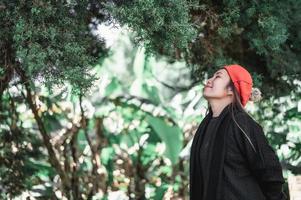 vista lateral de una joven asiática feliz vestida de invierno relajándose respirando aire fresco al aire libre