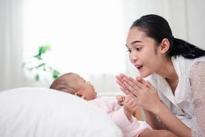 crianza de la madre y vida del nacimiento del recién nacido. mamá y bebé jugando en un dormitorio soleado, familia divirtiéndose juntos. cuidado de niños, concepto de maternidad. foto