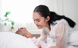 Mother Parenting and newborn birth life. Mom and baby boy playing in sunny bedroom, Family having fun together. childcare, maternity concept. photo