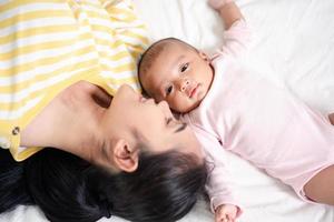 crianza de la madre y vida del nacimiento del recién nacido. mamá y bebé jugando en un dormitorio soleado, familia divirtiéndose juntos. cuidado de niños, concepto de maternidad. foto