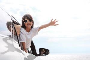 Little Girls happy traveling car travel enjoy holidays and relaxation. Hatchback Car travel driving road trip of family summer vacation in car at sunset,together get the atmosphere go to destination photo