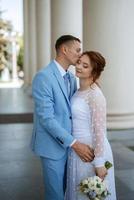 bride in a light wedding dress to the groom in a blue suit photo