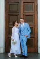bride in a light wedding dress to the groom in a blue suit photo