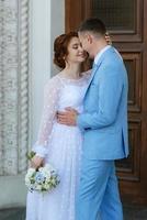 bride in a light wedding dress to the groom in a blue suit photo