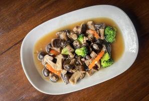 champiñones salteados con verduras de zanahoria y brócoli, champiñones shiitake con salsa de ostras cocinando comida en un plato blanco, champiñones shiitake cocinados al freír foto