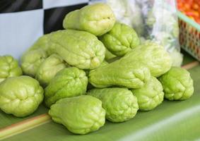 frutos frescos de chayote sechium edulis sobre fondo de hoja chayote o calabaza dulce - cucurbitaceae foto