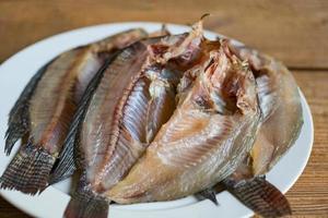 dried fish on white plate, tilapia fish for cooking food on wooden - food preservation dry fish photo