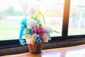 colorful flower pot on the wooden table with window Multi-colored bouquet of different flowers on the windowsill photo