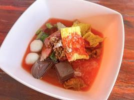 Food Thai style noodle with assorted tofu and fish ball in red soup - Asian food style pink seafood flat noodles on soup bowl photo